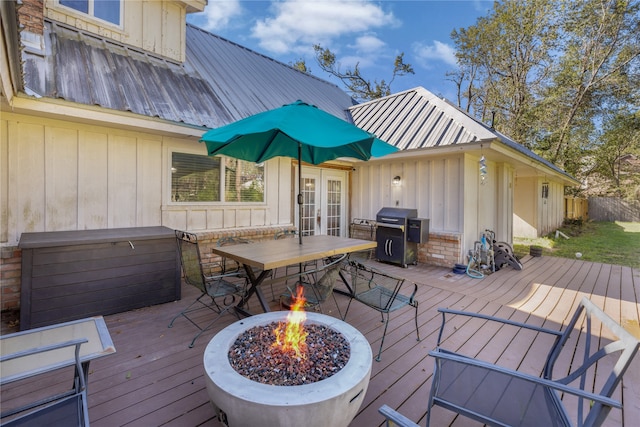 deck with a grill, french doors, and a fire pit