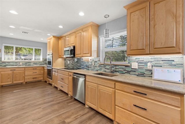 kitchen featuring pendant lighting, light brown cabinets, sink, light wood-type flooring, and stainless steel appliances