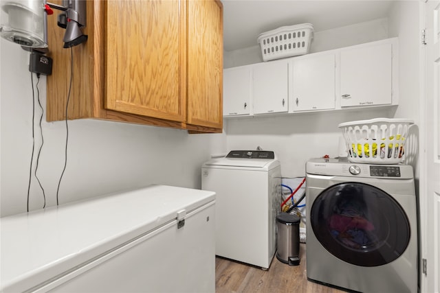 washroom with washer and dryer, cabinets, and light hardwood / wood-style floors