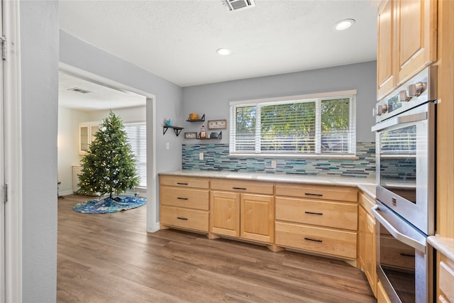 kitchen featuring hardwood / wood-style floors, decorative backsplash, double oven, and light brown cabinetry