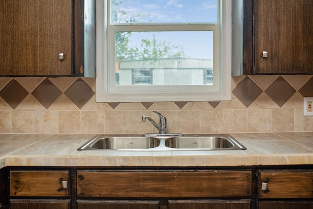 kitchen with dark brown cabinets, backsplash, and sink