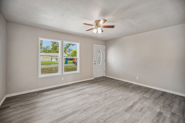 empty room featuring a textured ceiling, light hardwood / wood-style flooring, and ceiling fan