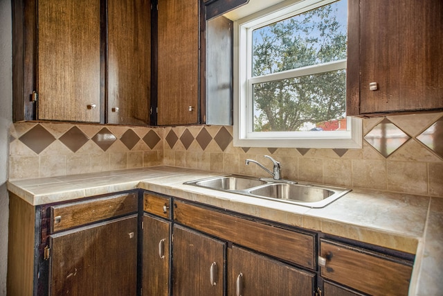 kitchen featuring backsplash, sink, and dark brown cabinets