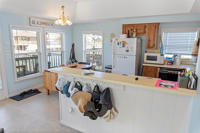 kitchen featuring hanging light fixtures, kitchen peninsula, a chandelier, white appliances, and light tile patterned floors