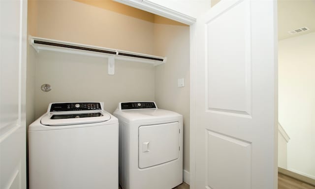 laundry area with washer and dryer and light hardwood / wood-style flooring