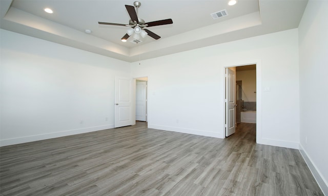 unfurnished bedroom with a tray ceiling, ceiling fan, and light hardwood / wood-style floors