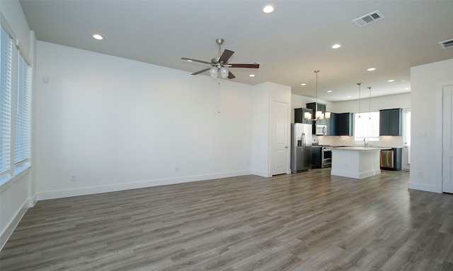 unfurnished living room with ceiling fan with notable chandelier, dark hardwood / wood-style flooring, and sink