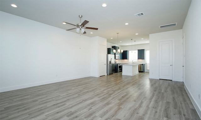 unfurnished living room with ceiling fan, sink, and light hardwood / wood-style flooring