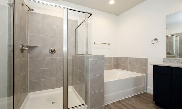 bathroom with hardwood / wood-style floors, vanity, and plus walk in shower