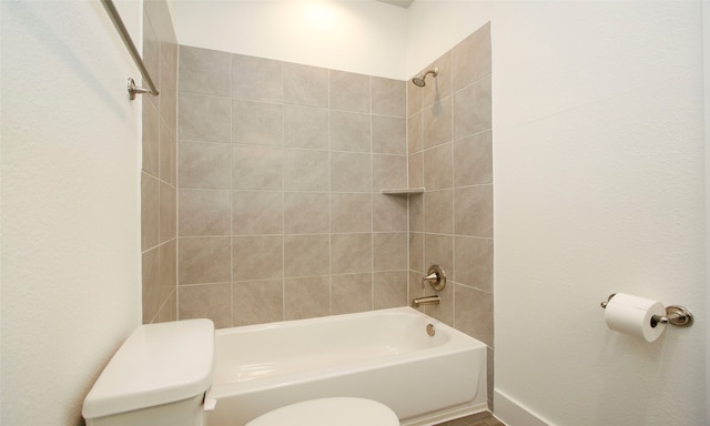 bathroom featuring tiled shower / bath combo and toilet