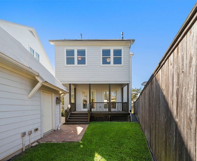 back of property featuring a lawn and covered porch