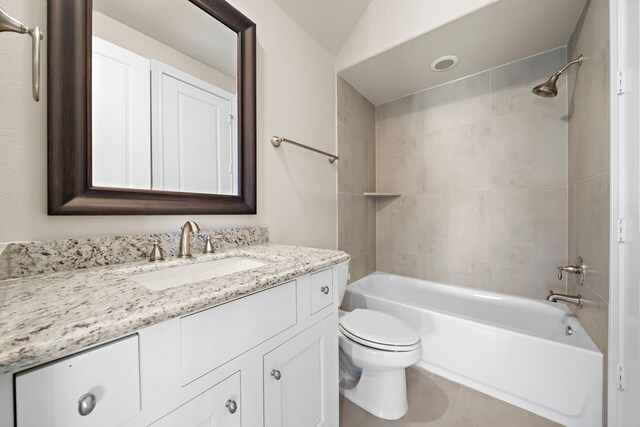 full bathroom with vanity, tiled shower / bath combo, toilet, and lofted ceiling