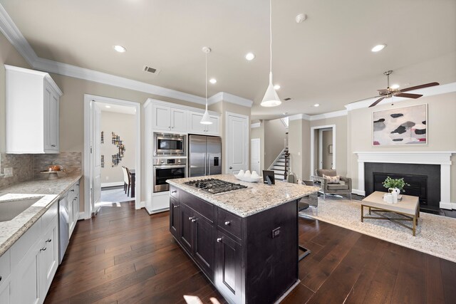 kitchen featuring stainless steel appliances, a kitchen island, backsplash, pendant lighting, and white cabinets