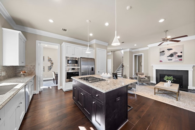 kitchen featuring white cabinetry, built in appliances, a center island, decorative light fixtures, and decorative backsplash