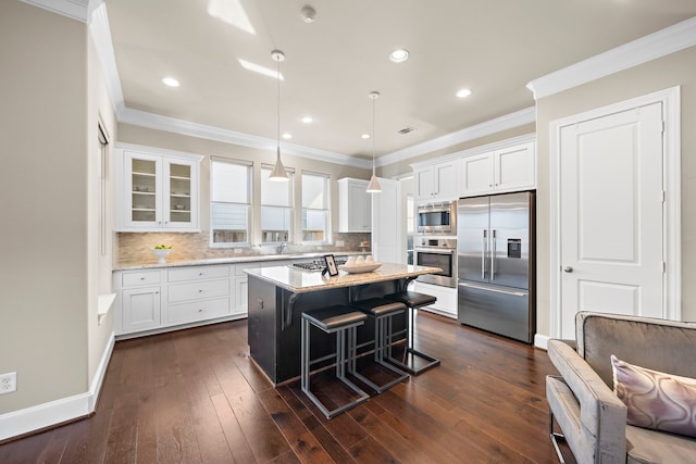 kitchen with pendant lighting, a center island, a breakfast bar area, white cabinetry, and stainless steel appliances