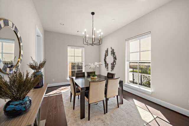 dining space with light hardwood / wood-style floors and a notable chandelier