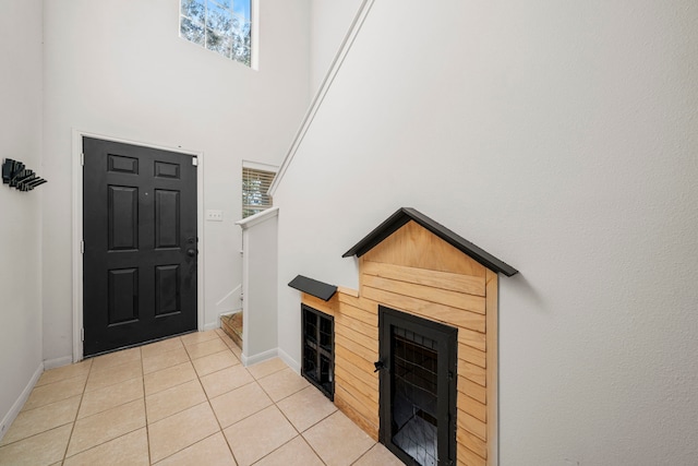 tiled foyer with a fireplace and a high ceiling