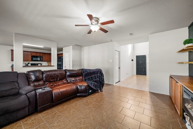 living room with ceiling fan, light tile patterned flooring, and a textured ceiling