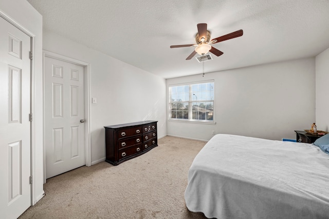 carpeted bedroom featuring ceiling fan and a textured ceiling