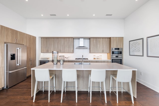 kitchen with wall chimney range hood, dark hardwood / wood-style floors, a spacious island, a breakfast bar area, and appliances with stainless steel finishes