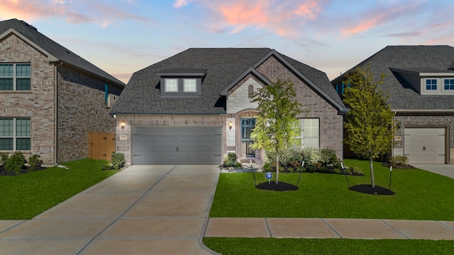 french country style house featuring a garage and a lawn