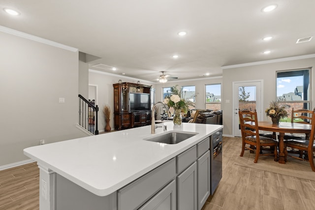 kitchen with gray cabinetry, a center island with sink, sink, light hardwood / wood-style flooring, and ceiling fan