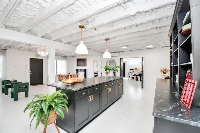 kitchen with decorative light fixtures, a center island, and dark stone counters