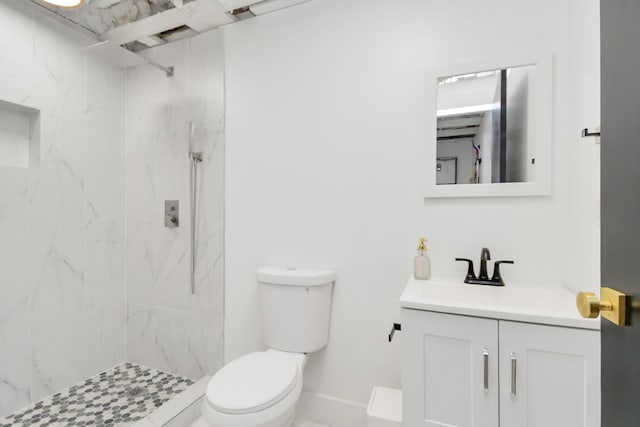 bathroom with a tile shower, vanity, and toilet