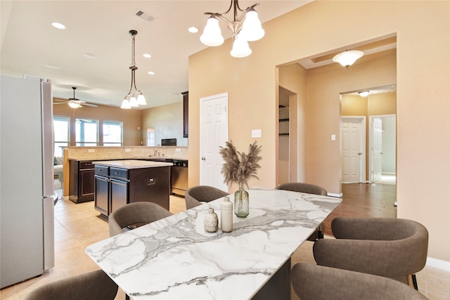 dining space with ceiling fan with notable chandelier and light wood-type flooring