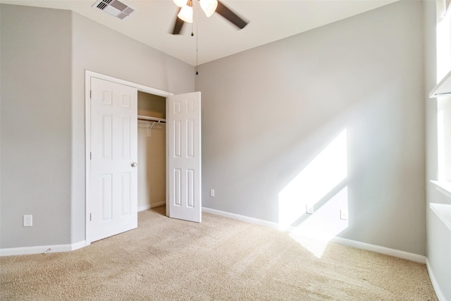 unfurnished bedroom with a closet, light colored carpet, and ceiling fan