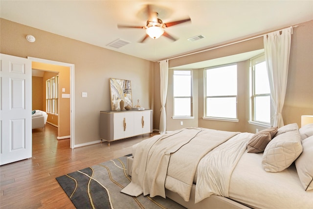 bedroom with wood-type flooring, multiple windows, and ceiling fan