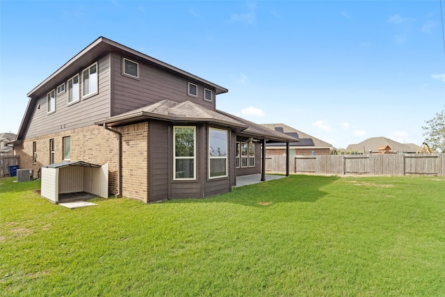 back of house featuring central AC unit, a storage shed, and a yard