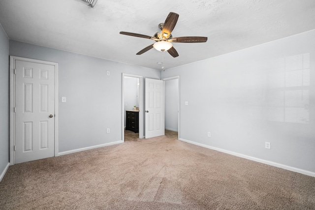 unfurnished bedroom with ceiling fan, carpet floors, and ensuite bathroom