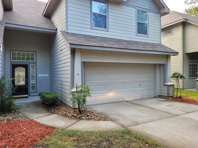 view of front of house featuring concrete driveway, a garage, and a shingled roof