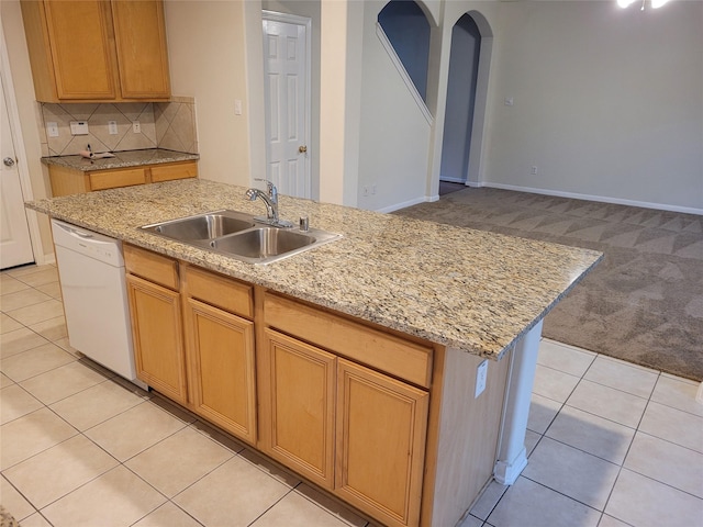 kitchen featuring backsplash, white dishwasher, a center island with sink, sink, and light colored carpet