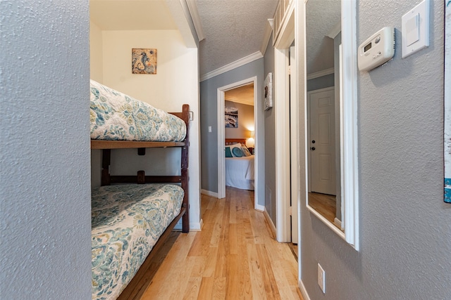 bedroom with crown molding, light hardwood / wood-style flooring, and a textured ceiling