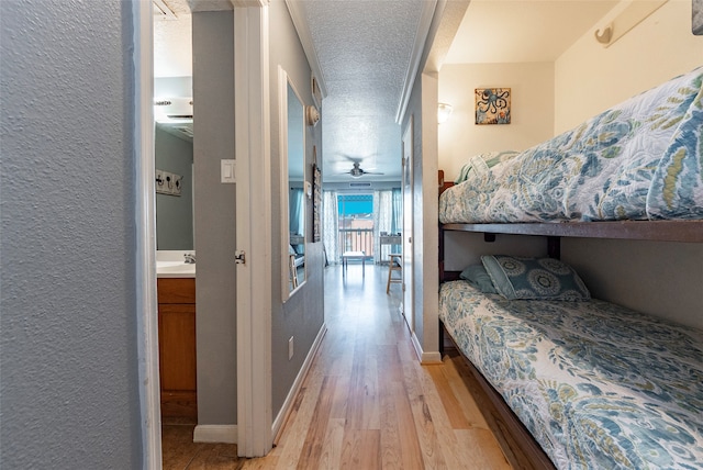 bedroom featuring a textured ceiling, ensuite bathroom, light hardwood / wood-style flooring, and sink