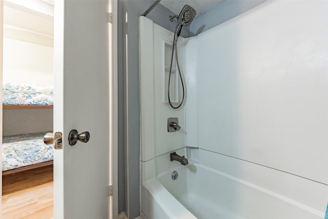 bathroom with shower / tub combination, a textured ceiling, and hardwood / wood-style flooring