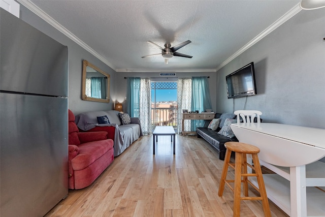 living room featuring crown molding, light hardwood / wood-style flooring, ceiling fan, and a textured ceiling