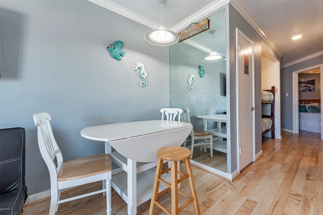 dining room featuring light hardwood / wood-style floors, a textured ceiling, and ornamental molding