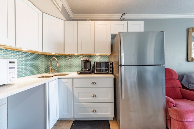 kitchen with sink, crown molding, stainless steel fridge, light hardwood / wood-style floors, and white cabinetry