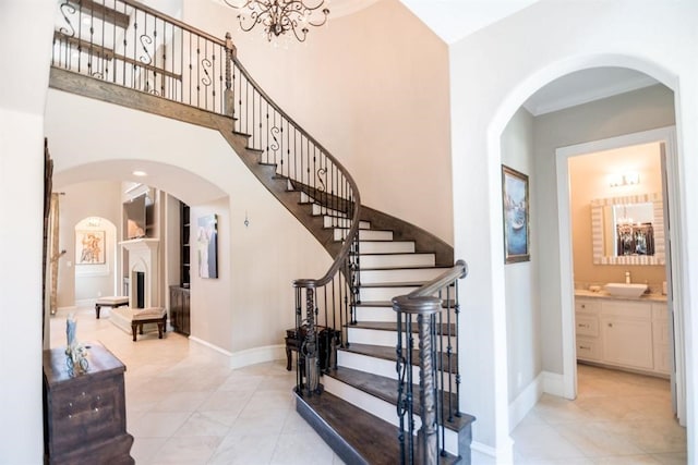 stairs with tile patterned flooring, a towering ceiling, and sink