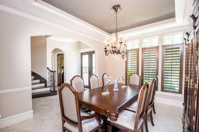 tiled dining space featuring a chandelier, french doors, a wealth of natural light, and a tray ceiling