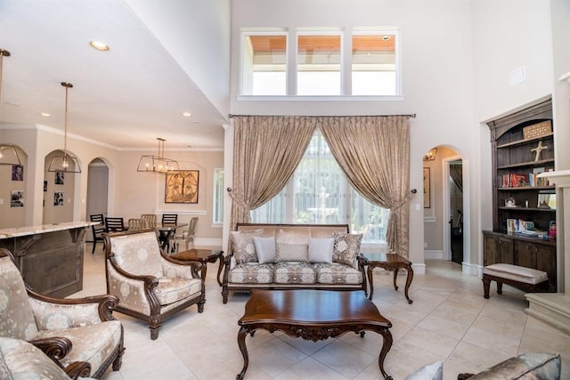 sitting room with a notable chandelier, light tile patterned flooring, a towering ceiling, and crown molding