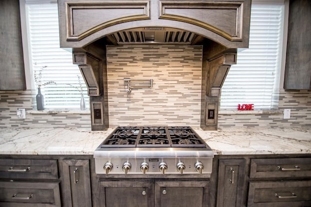 kitchen featuring light stone countertops, dark brown cabinetry, tasteful backsplash, and stainless steel gas cooktop