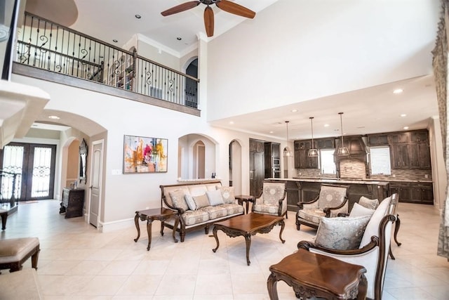 tiled living room featuring french doors, a towering ceiling, ceiling fan, and crown molding