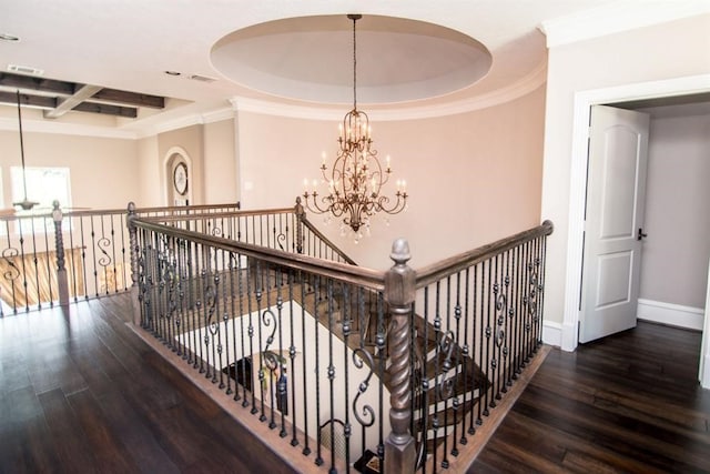 hall with coffered ceiling, a raised ceiling, crown molding, an inviting chandelier, and dark hardwood / wood-style floors