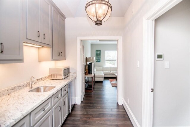 kitchen with gray cabinets, light stone countertops, sink, and dark hardwood / wood-style floors