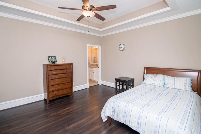 bedroom featuring connected bathroom, ceiling fan, dark hardwood / wood-style floors, a tray ceiling, and ornamental molding