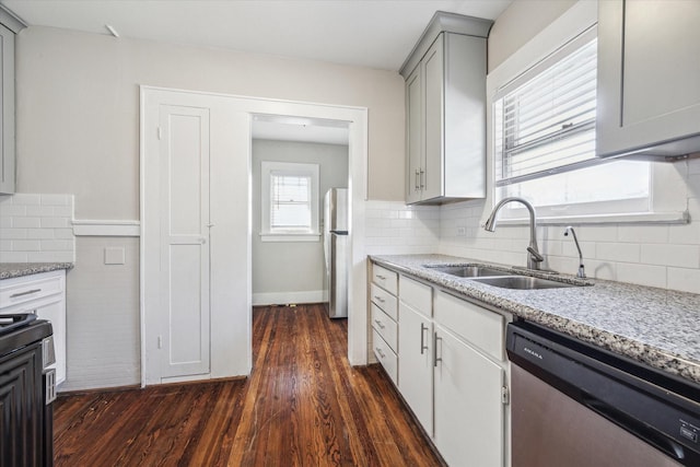 kitchen featuring sink, appliances with stainless steel finishes, backsplash, dark hardwood / wood-style floors, and light stone counters